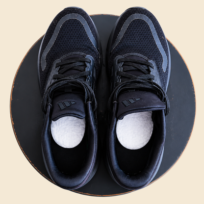 Pair of black trainers with white cotton pads inside, top view