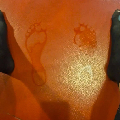 Two damp footprints on an orange gym floor